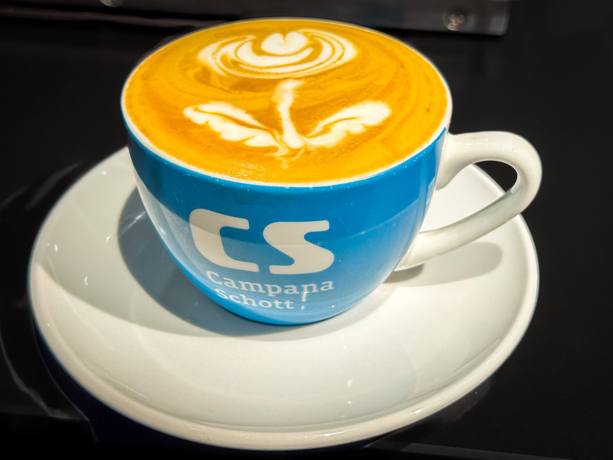 Eine Cappuccino-Tasse im Büro, Symbol für den Start in den Arbeitstag mit einer klaren Entscheidung: ins Büro oder nicht?