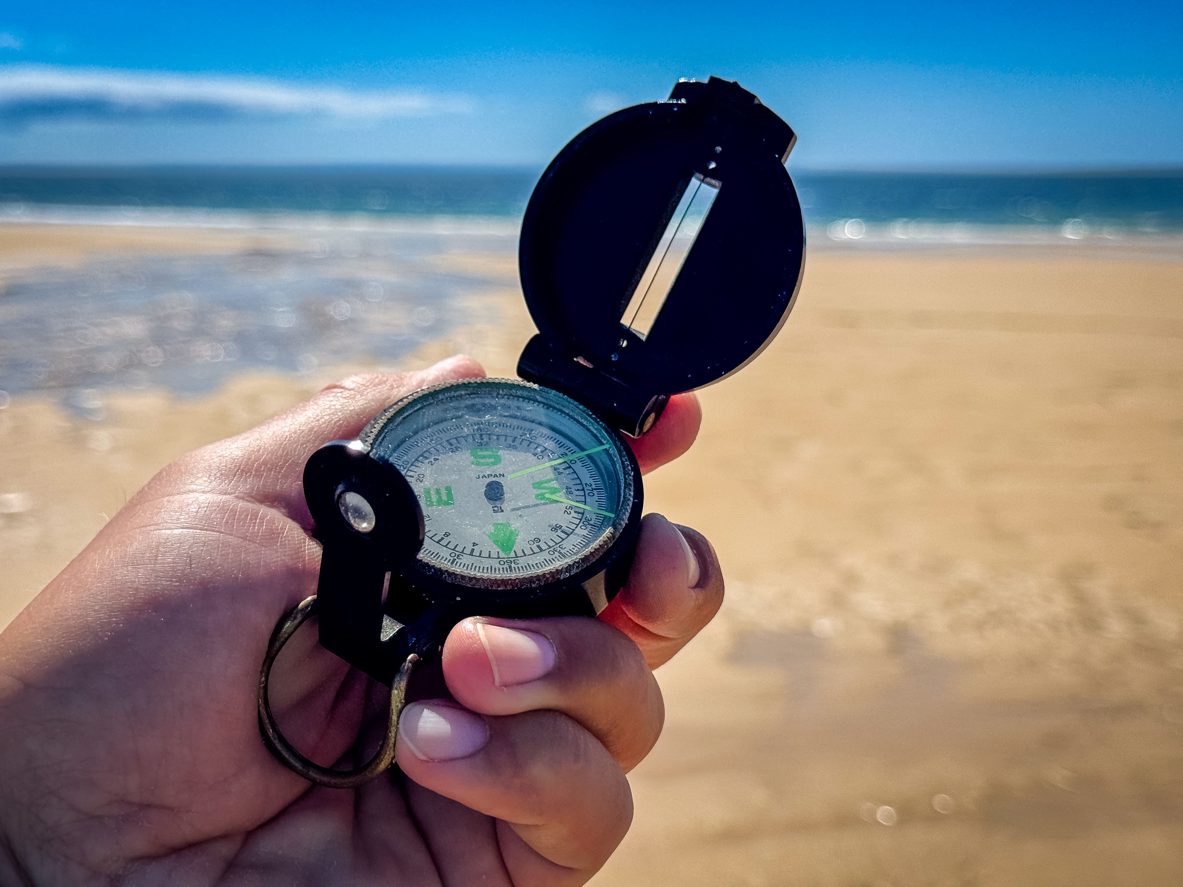 Symbol image – compass on the beach